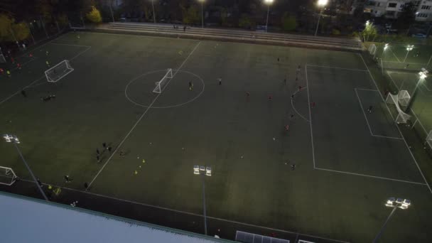 Veduta aerea del campo da calcio di notte con i giocatori di calcio dilettanti che giocano il gioco in città - Filmati, video