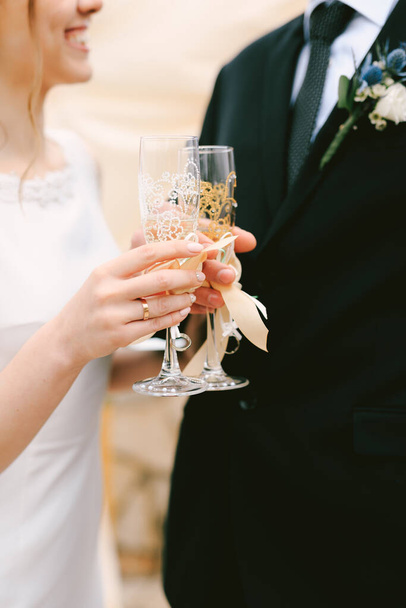 Bride and groom clink glasses of champagne. Close up - 写真・画像