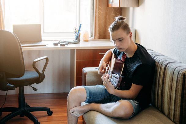 Guitar lessons for beginners. Caucasian teenager playing guitar, having Online Guitar Lessons, enjoying favorite hobby, leisure. Acoustic guitars for beginners. - Foto, Imagem
