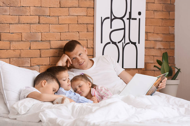 Isä lukee kirjaa ja vie lapset nukkumaan. Perhe nukkumaanmenoaika - Valokuva, kuva