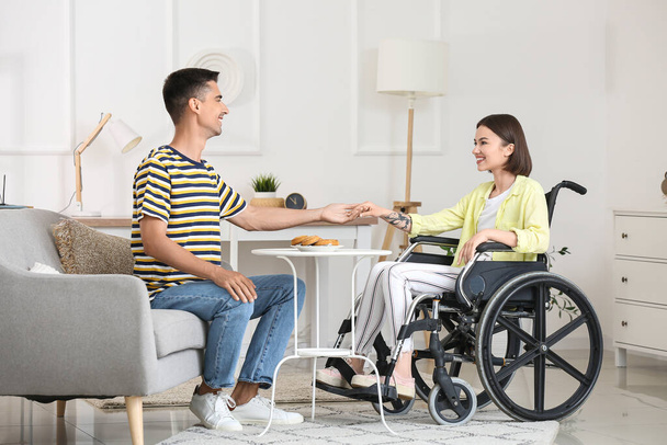 Young woman in wheelchair and her husband at home - Photo, image