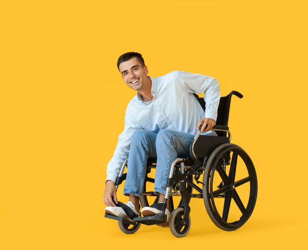 Jonge man in rolstoel op kleur achtergrond - Foto, afbeelding