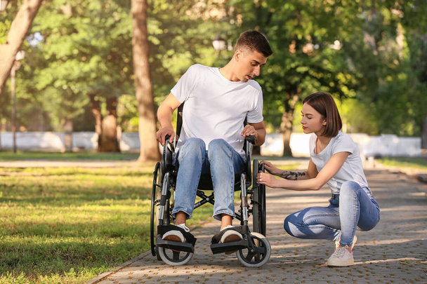 Mladý muž s tělesným postižením a jeho žena mají problém s invalidním vozíkem v parku - Fotografie, Obrázek