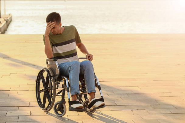 Depressiver junger Mann mit körperlicher Behinderung im Freien - Foto, Bild