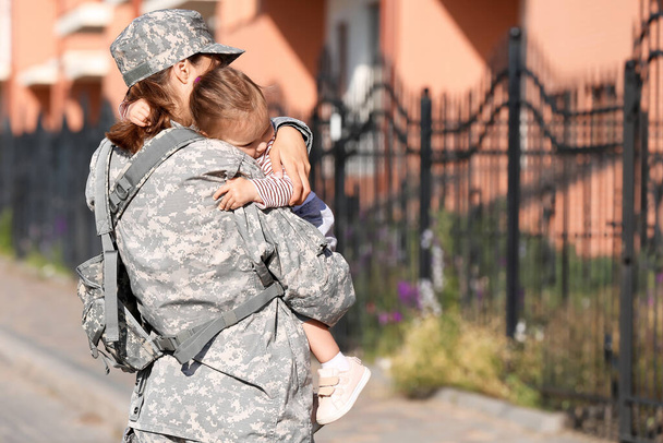 Mujer soldado con su pequeña hija al aire libre - Foto, Imagen