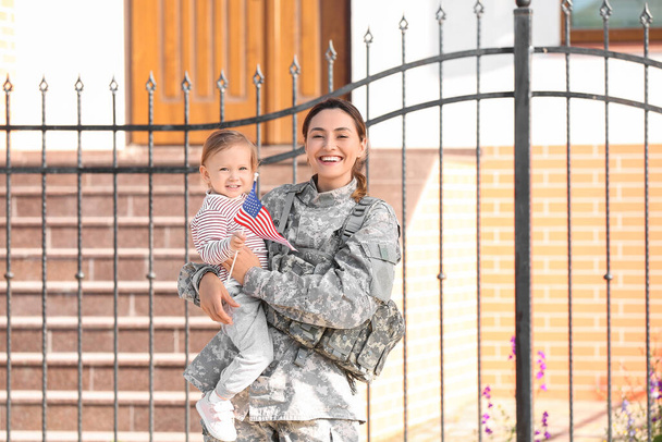 Mujer soldado y su hija pequeña con bandera de EE.UU. al aire libre - Foto, imagen