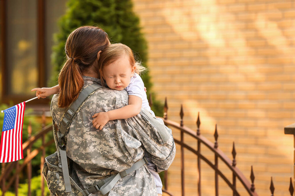 Vrouwelijke soldaat en haar dochtertje met USA vlag buiten - Foto, afbeelding