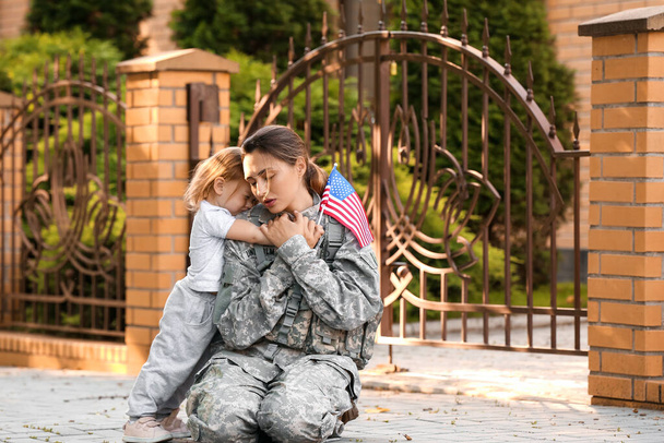 Female soldier and her little daughter with USA flag outdoors - Photo, Image