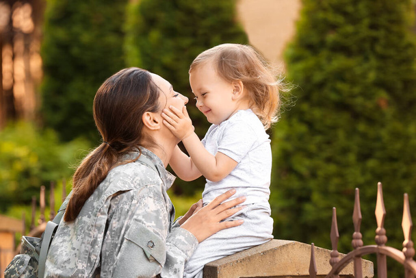 Female soldier with her little daughter outdoors - Photo, Image