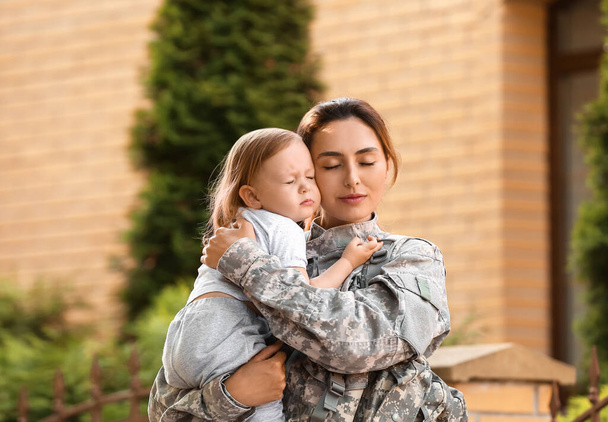 Mujer soldado con su pequeña hija al aire libre - Foto, Imagen