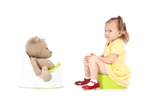 Söpö vauva tyttö ja lelu karhu istuu potties vastaan valkoinen tausta - Valokuva, kuva