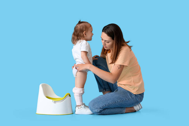 Mother potty training her little daughter on color background - Photo, Image