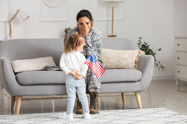 Female soldier and her little daughter with USA flag at home - Fotografie, Obrázek