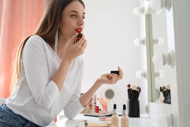 Hermosa mujer aplicando lápiz labial rojo en el vestidor - Foto, imagen