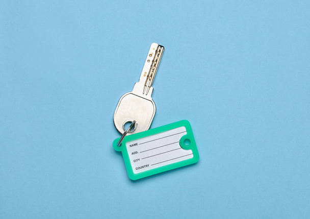 Key with plastic tag on blue background - Photo, Image