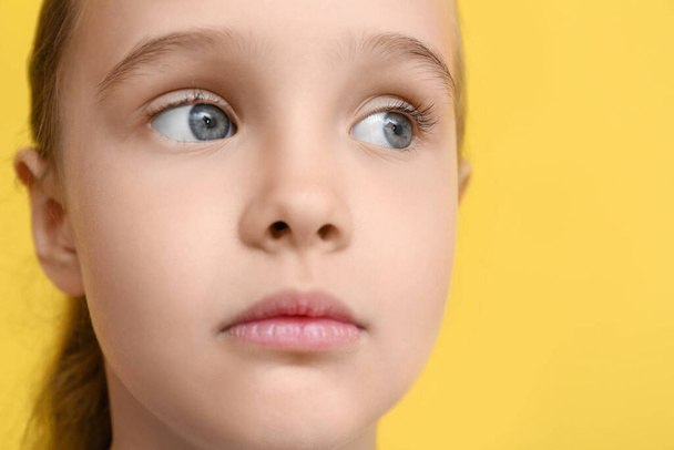 Portrait of cute little girl on yellow background, closeup - Photo, Image