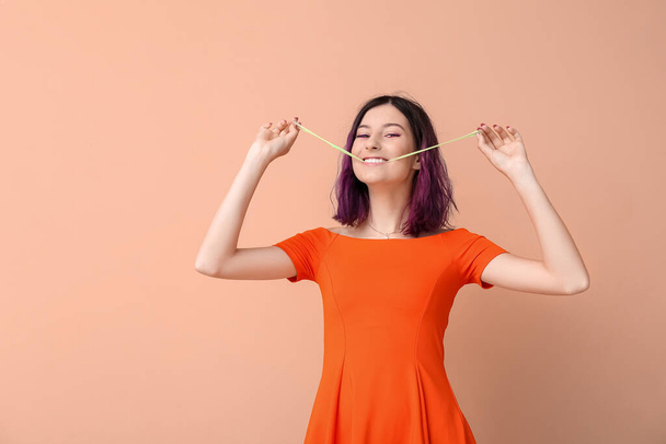 Young woman with purple hair and chewing gum on beige background - Foto, Imagen