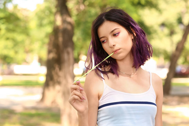 Молодая женщина с фиолетовыми волосами жевательная резинка в парке - Фото, изображение