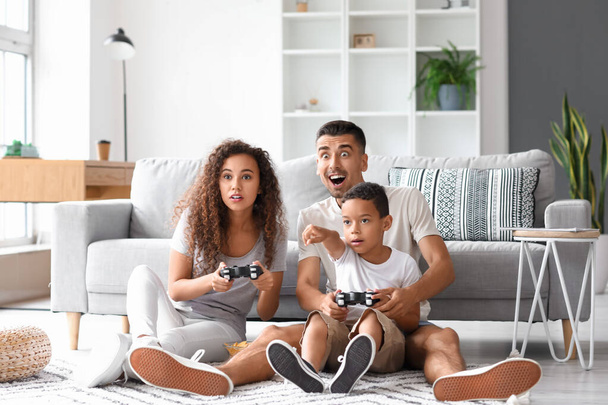 Ευτυχισμένη διαφυλετική οικογένεια που παίζει βιντεοπαιχνίδι στο σπίτι - Φωτογραφία, εικόνα