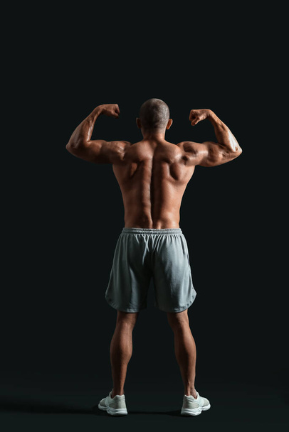Male bodybuilder on dark background, back view - Fotoğraf, Görsel