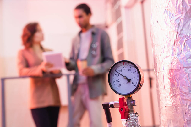 selective focus of manometer of data center cooling system near blurred interracial engineers - Photo, Image