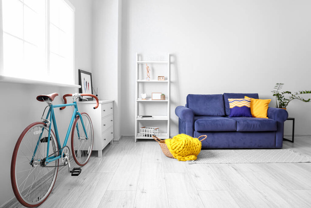 Elegante interior con bicicleta y sofá azul en la habitación - Foto, imagen