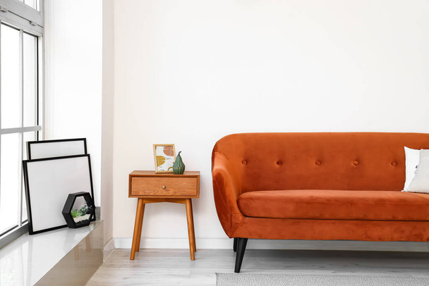 Sofá elegante e mesa de cabeceira perto da parede clara - Foto, Imagem