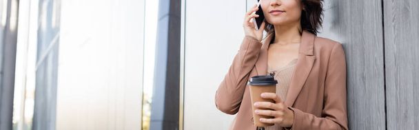 cropped view of young woman with takeaway drink talking on mobile phone outdoors, banner - Photo, Image