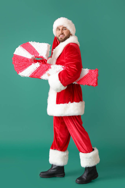 Santa Claus with candy cane pinata on green background - Photo, Image