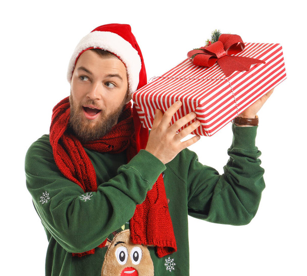 Handsome young man with Christmas gift on white background - Фото, зображення