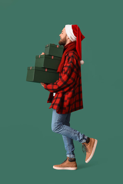Going man with Christmas gifts on color background - Фото, изображение