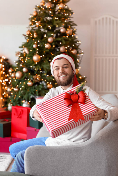 Handsome man with gift at home on Christmas eve - Foto, imagen