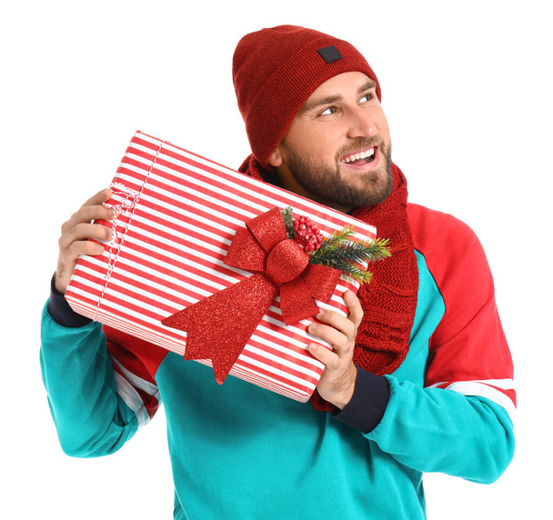 Handsome young man with Christmas gift on white background - Foto, Imagen
