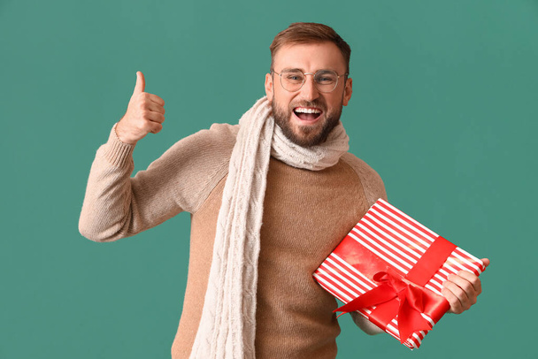 Счастливый человек с рождественским подарком на цветном фоне - Фото, изображение