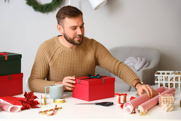 Hombre guapo embalaje regalos en casa en la víspera de Navidad - Foto, imagen