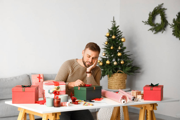 Όμορφος άντρας πακετάρει δώρα στο σπίτι την παραμονή των Χριστουγέννων - Φωτογραφία, εικόνα