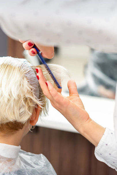 Žena kadeřnice styling krátké bílé vlasy mladé blondýny s rukama a hřeben ve kadeřnictví - Fotografie, Obrázek