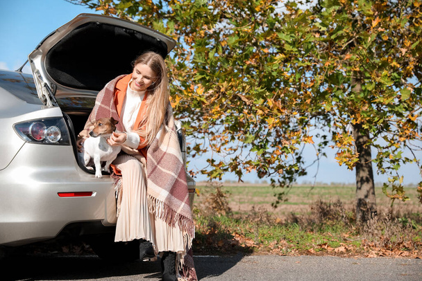 Krásná žena s roztomilým Jack Russel teriér sedí v kufru auta na podzim den - Fotografie, Obrázek