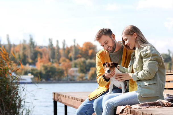 Lovely couple with cute Jack Russel terrier near river on autumn day - Photo, Image