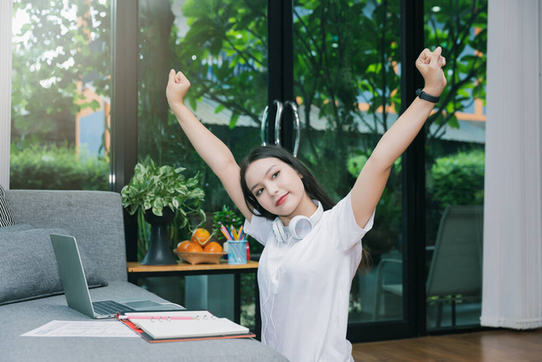 Happy woman with headphones raising hands at home workstation. - Photo, Image