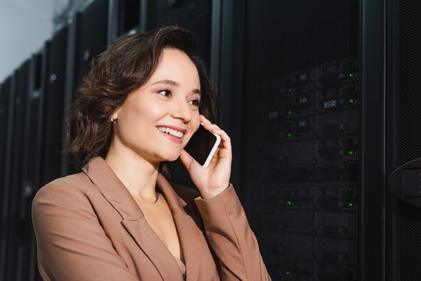 onnellinen insinööri puhuu matkapuhelimella lähellä palvelimia datakeskuksessa - Valokuva, kuva