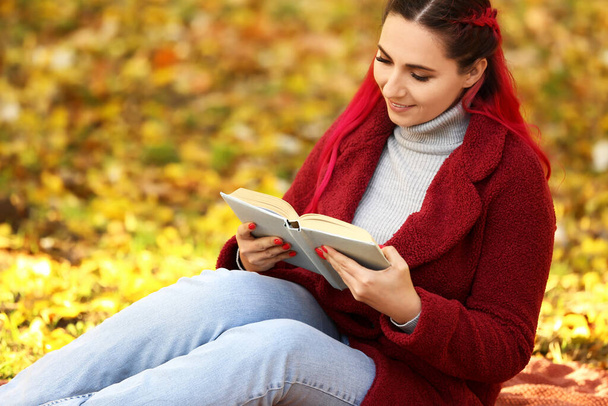 Beautiful woman with warm coat reading book in autumn park - Photo, image