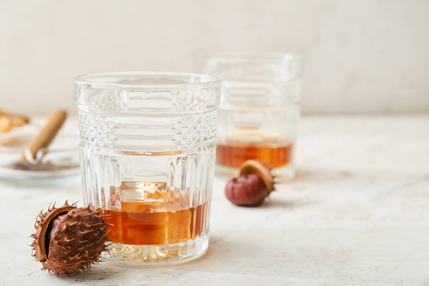 Glasses of cold chestnut whiskey on light background - Foto, afbeelding