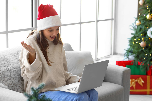 Young woman video chatting with friends at home on Christmas eve - Photo, Image