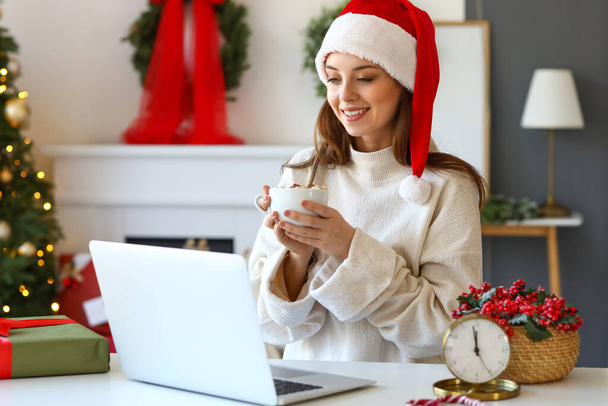 Young woman video chatting with friends at home on Christmas eve - Foto, imagen