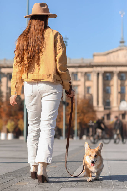 Стильная молодая женщина гуляет с симпатичной собакой Корги по городской площади - Фото, изображение