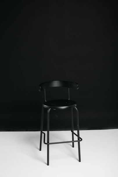 A stylish black chair stands on a black background in the studio room. The concept of a vacancy or an interview. Cinema, director's chair. - Foto, afbeelding