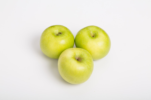 drie granny smith appels op witte teller - Foto, afbeelding