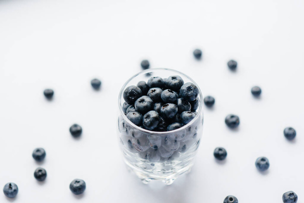 Beautiful ripe blueberries in a transparent glass glass on a white background. Healthy food, and vitamins. - Foto, Imagen
