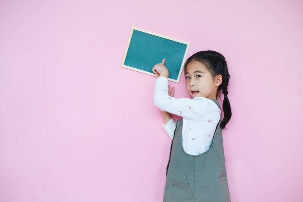 Portrait beautiful cute asian child girl on pink background with drawing board holding in hand - Photo, Image